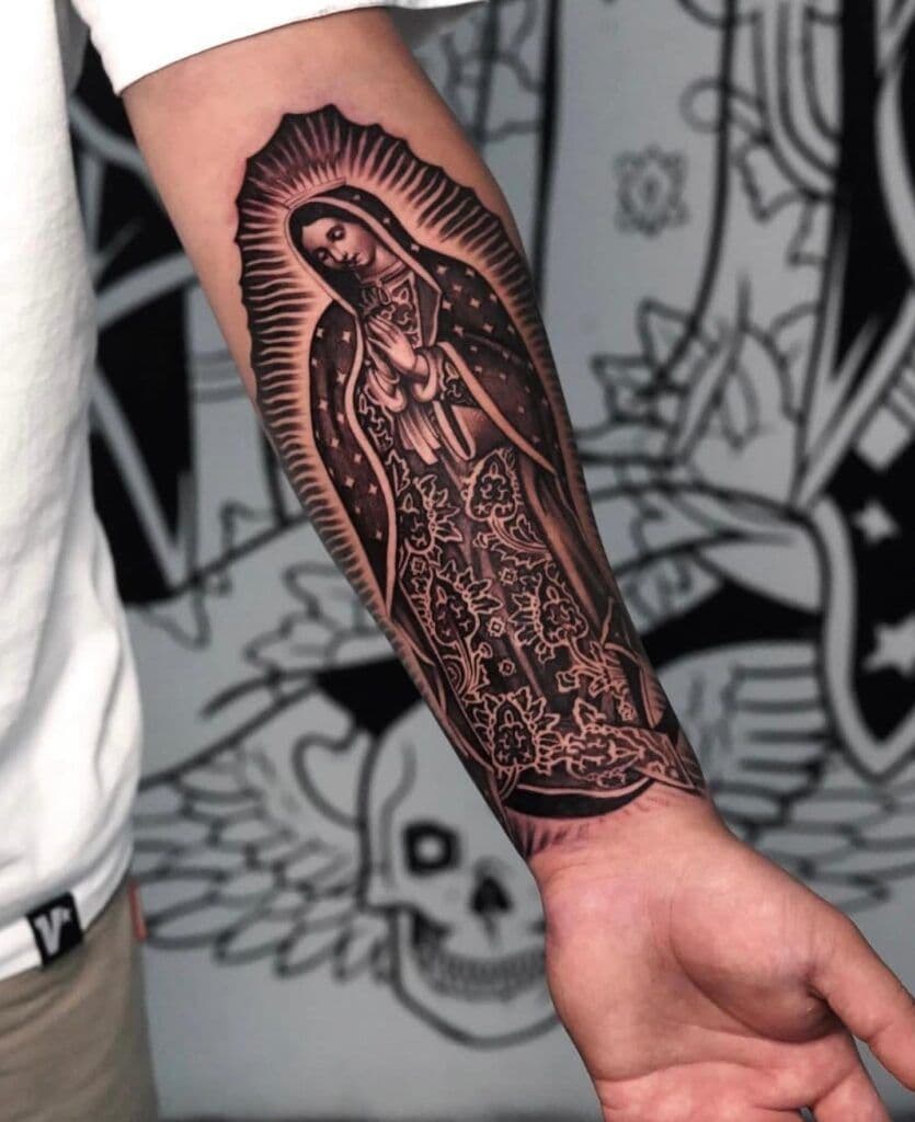 Tatuaje de la Virgen de Guadalupe en el brazo de un hombre en blanco y negro